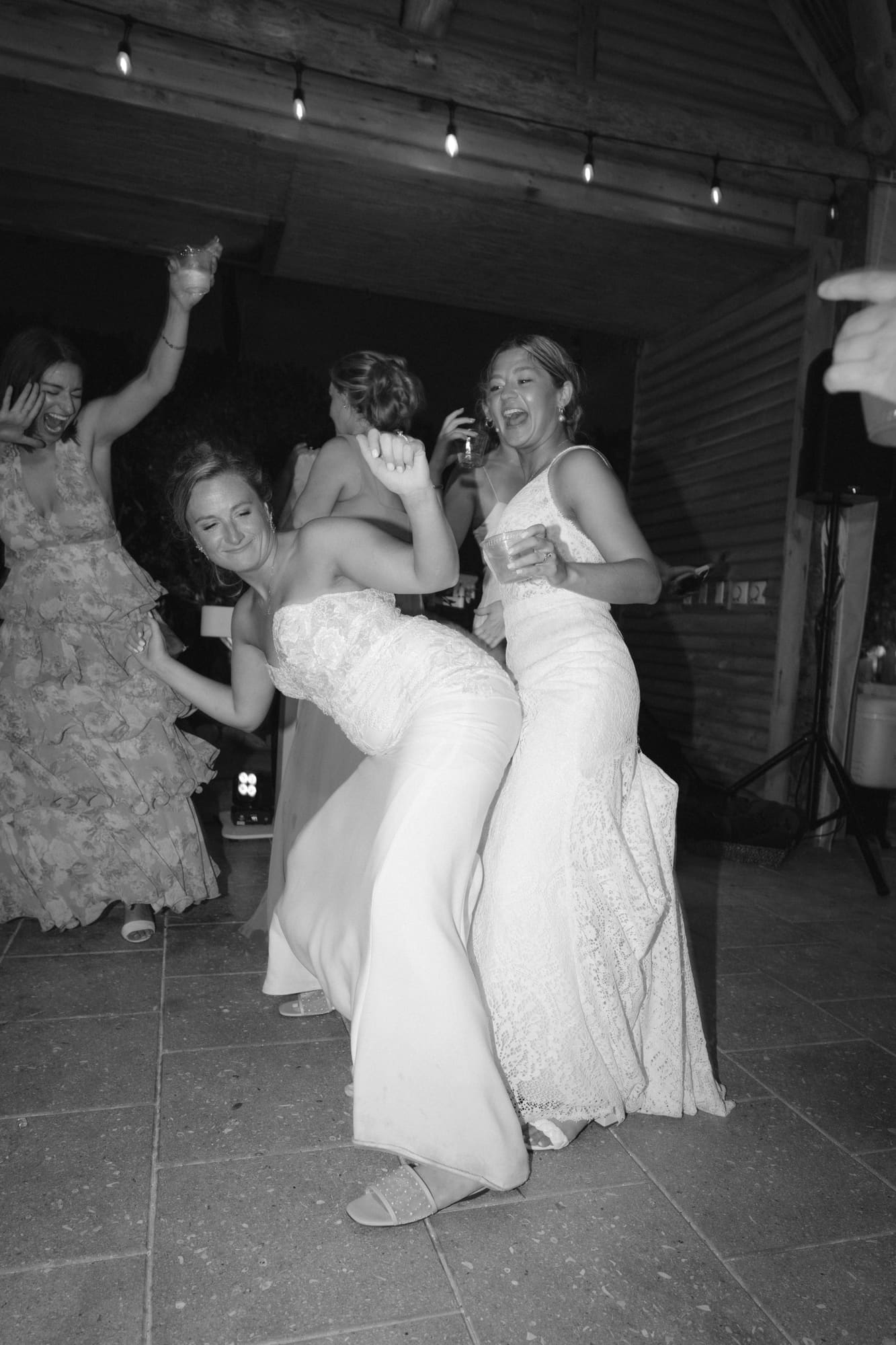 Two brides dancing together in a black-and-white candid at their Modern Era Weddings reception