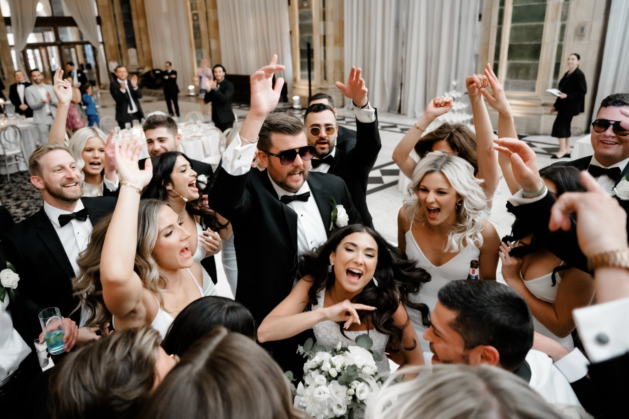 Bride and groom celebrating in the middle of a hands-up dance circle
