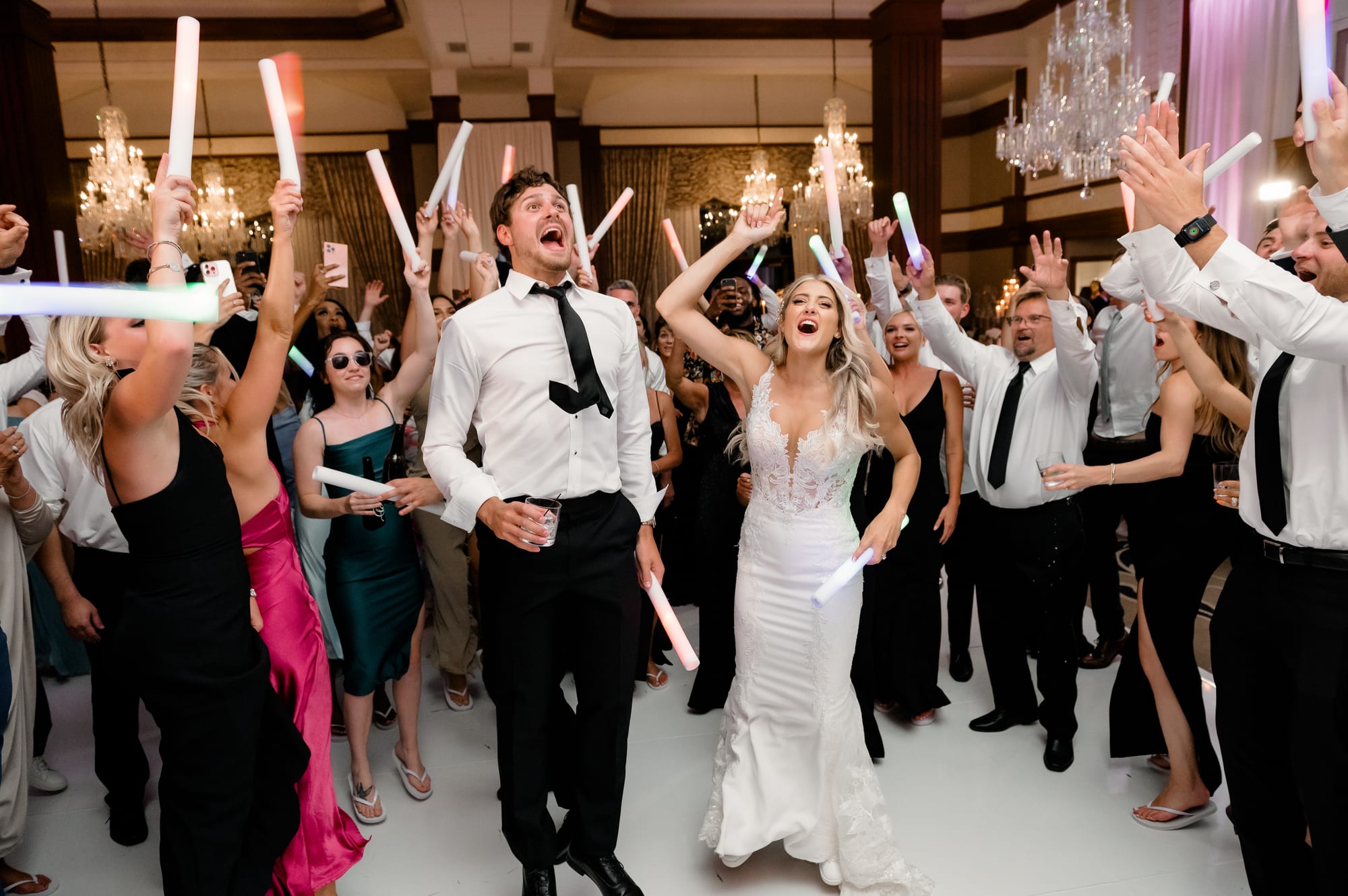 Bride and groom leading a glow-stick singalong as the crowd cheers in the Nemacolin ballroom