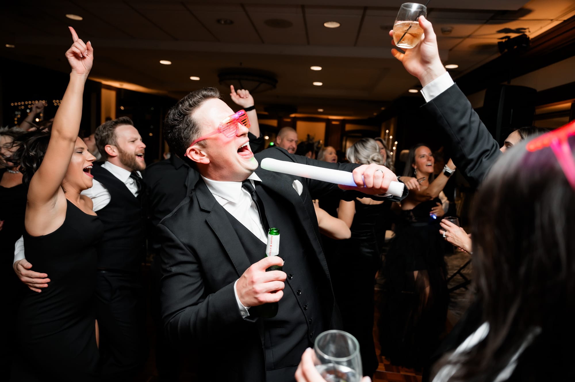 Groom in glow shades and a foam stick celebrating on the Sheraton Station Square dance floor